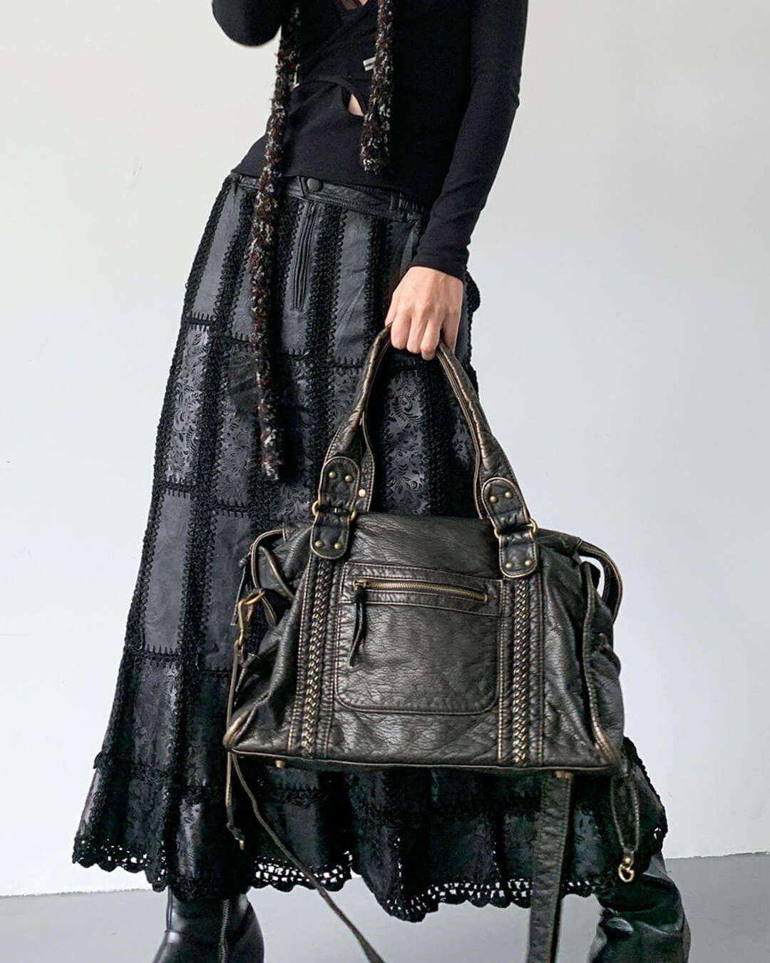 Black vintage-style weave bag held by handles, model in maxi skirt