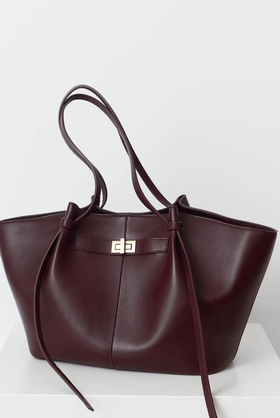 Burgundy leather tote bag with twist-lock strap detail, front view