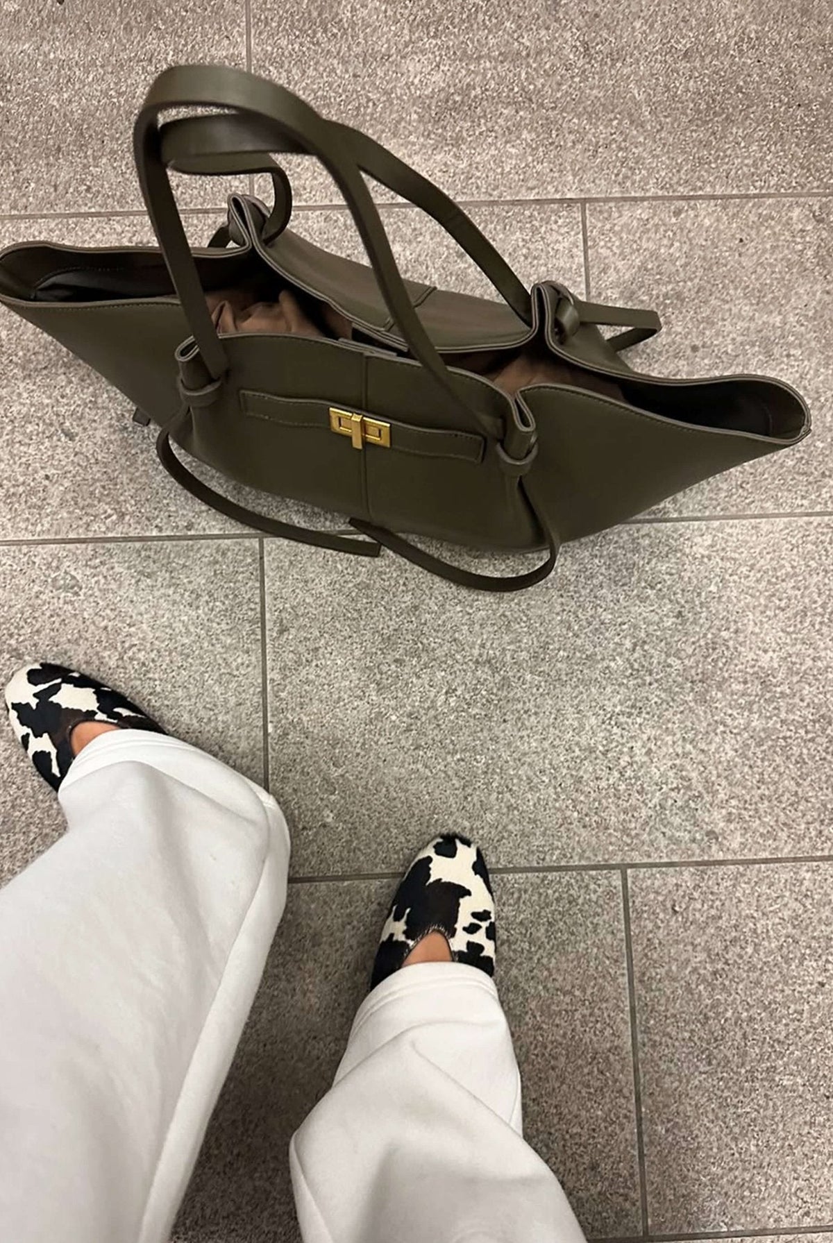 Olive green leather tote bag on floor, top-down view styled shot