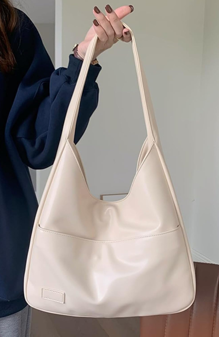 Ivory white leather slouchy shoulder bag held on model's arm