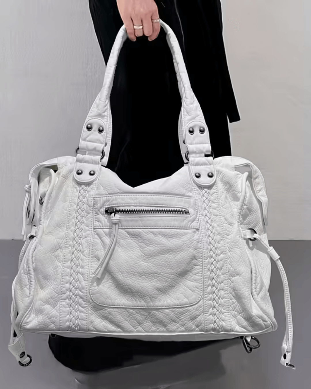 White vintage-style weave bag held by handles, model wearing black