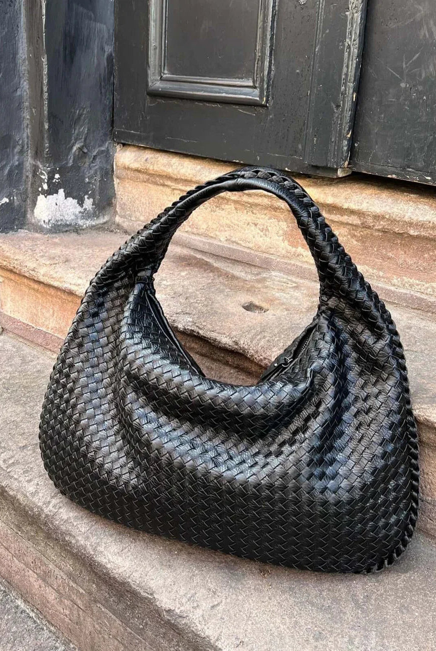 Black woven leather hobo bag resting on stone steps outdoors