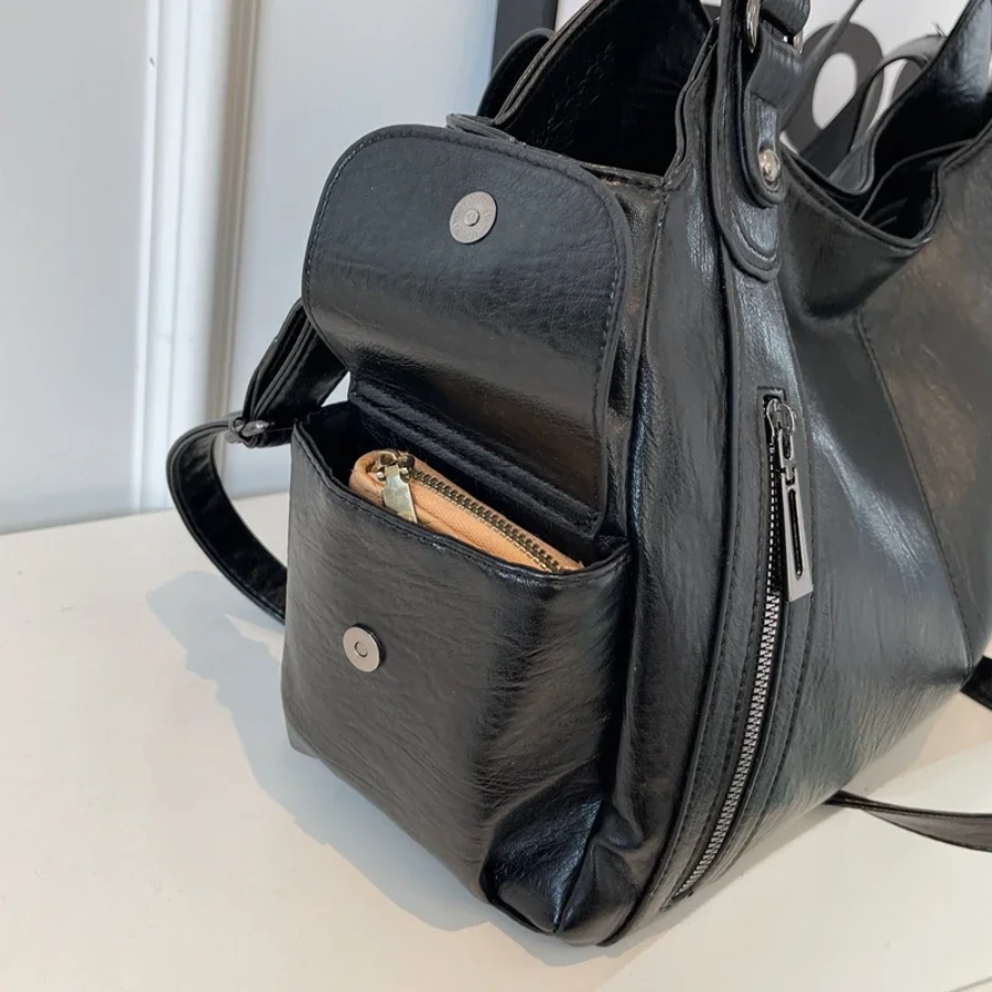 Midnight black leather shoulder bag, close-up of the side pocket