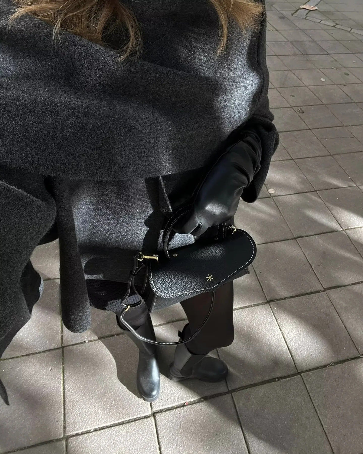 Close-up of charcoal cape scarf detail, model seated outdoors