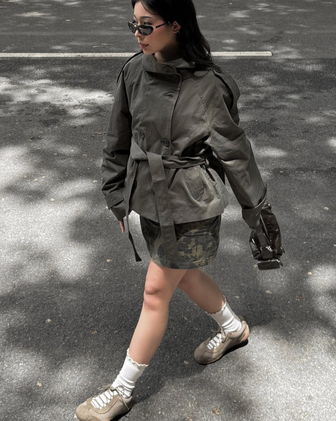 Olive green short belted trench coat, model walking outdoors