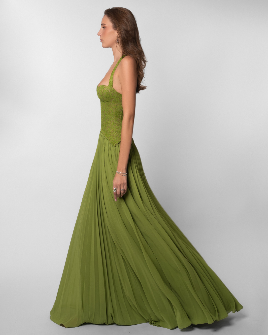 Olive green lace corset maxi dress with flowing pleated skirt, side view on model