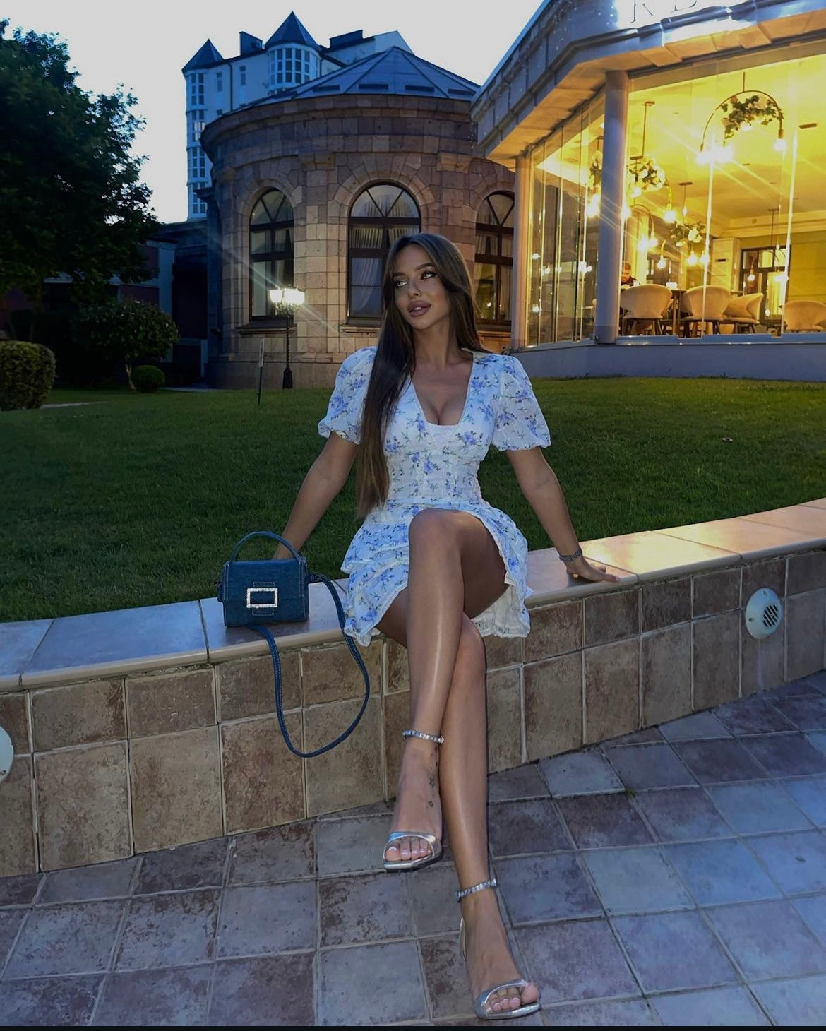 White and blue floral mini dress, model seated, crossed legs, evening light