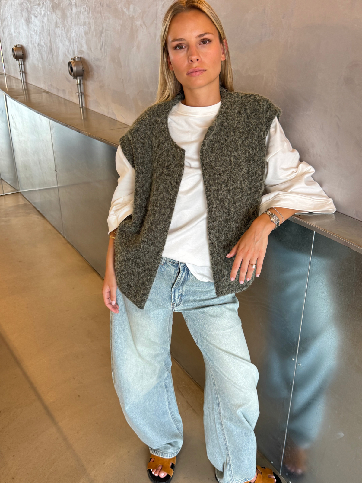 Green bouclé knit vest on model, leaning pose with jeans