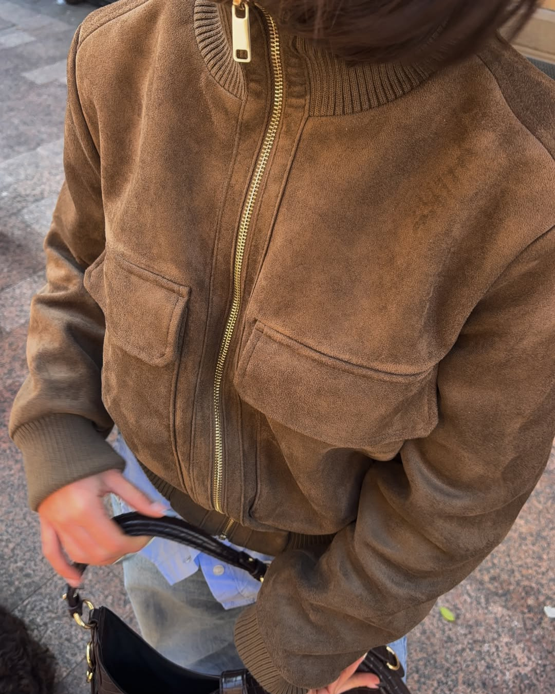 Close-up of brown suede bomber jacket zip and flap pockets