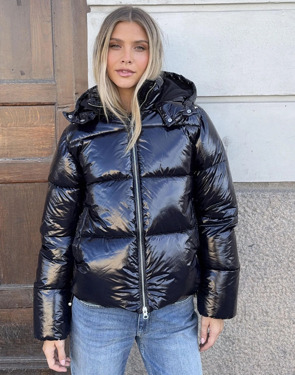 Black glossy hooded puffer jacket, front view on model