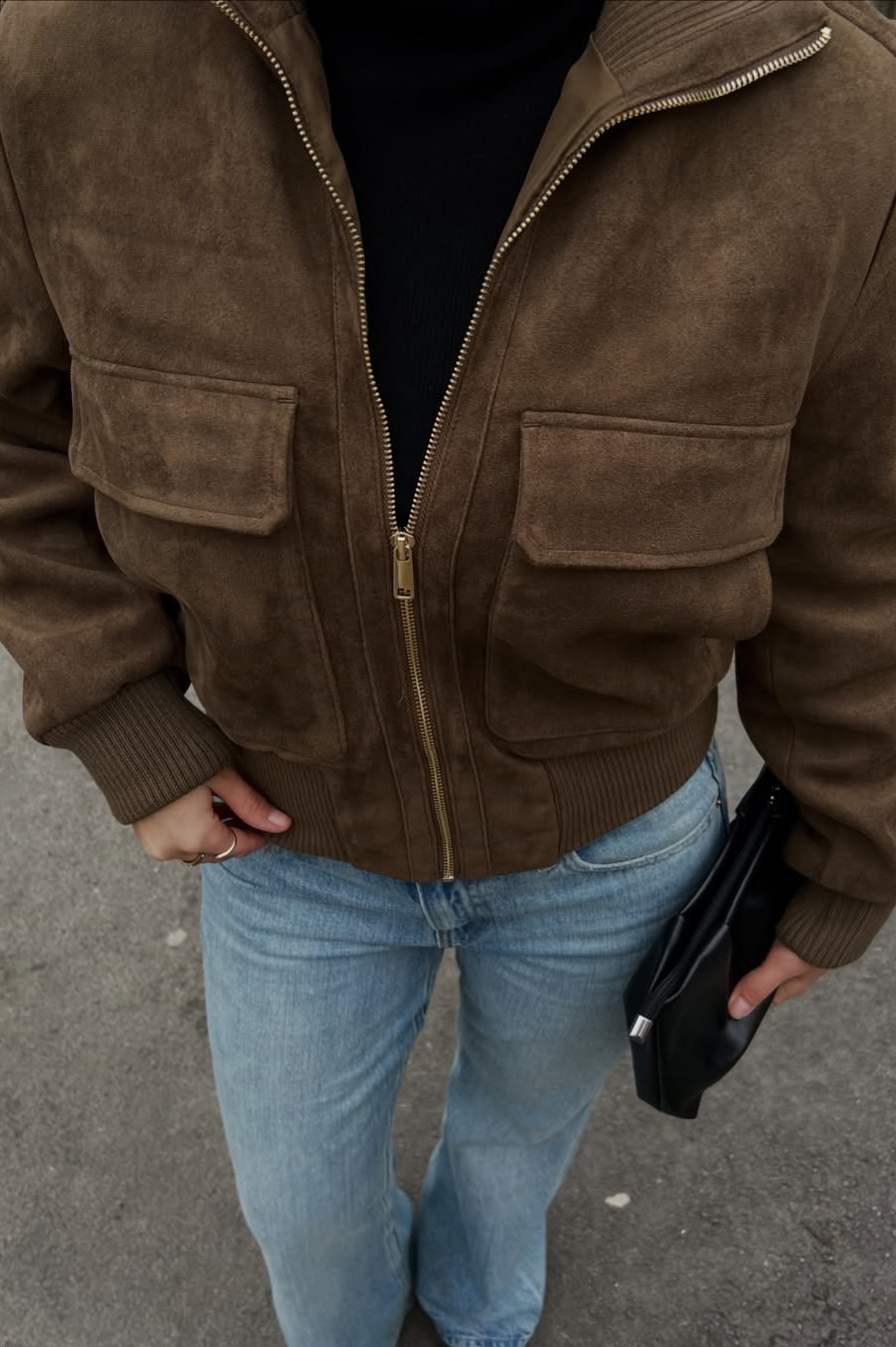 Close-up of brown suede bomber jacket with flap pockets on model