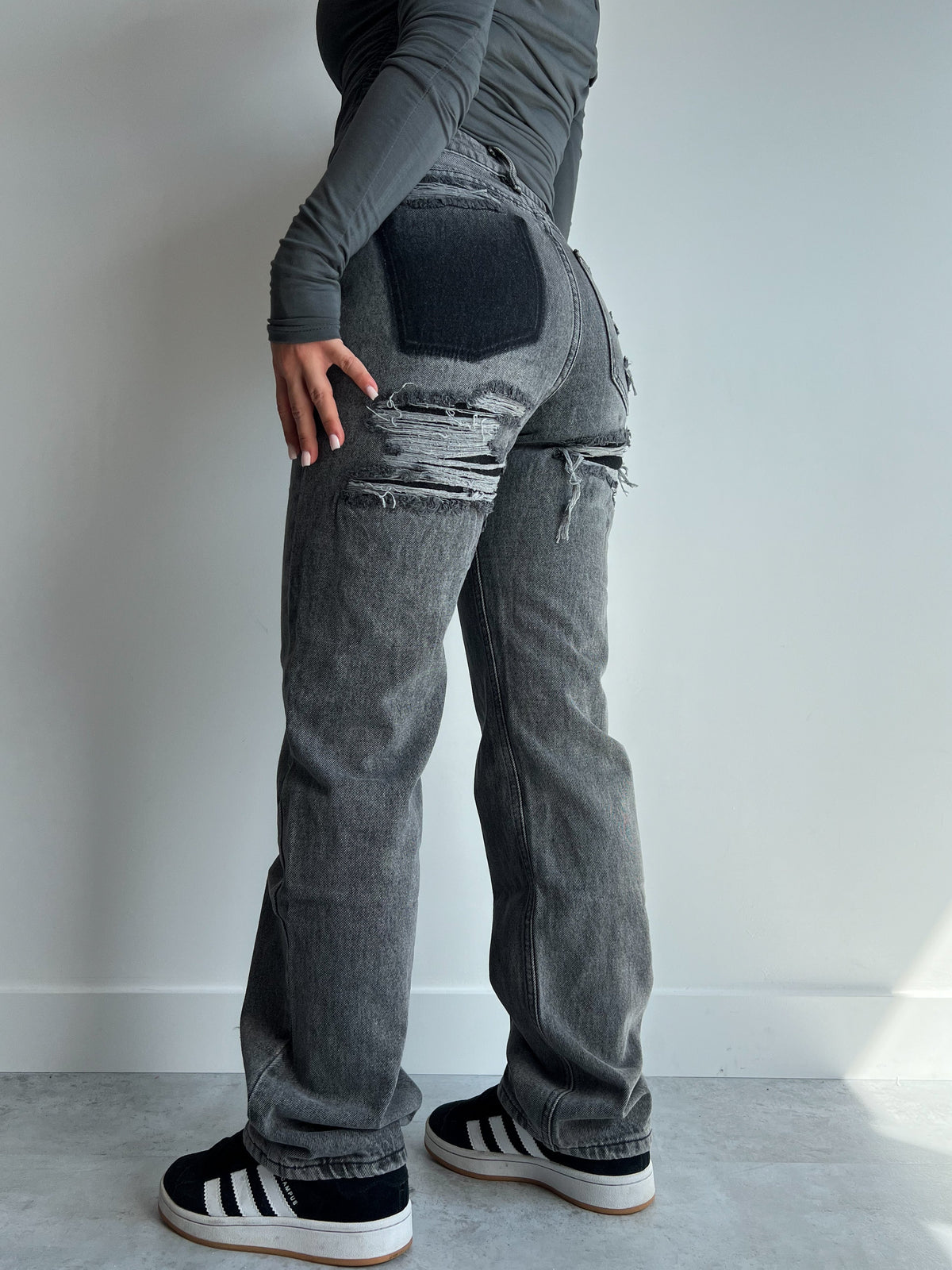Grey distressed wide-leg jeans with ripped thigh, back view on model
