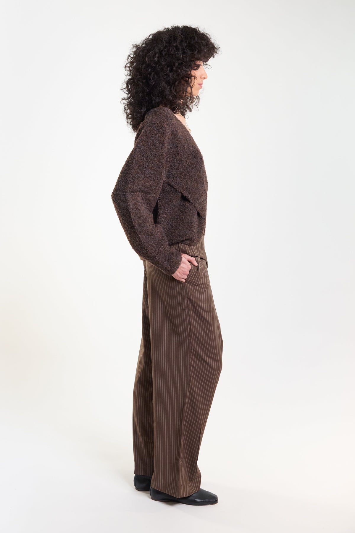 Brown pinstripe tailored trousers, side view on model