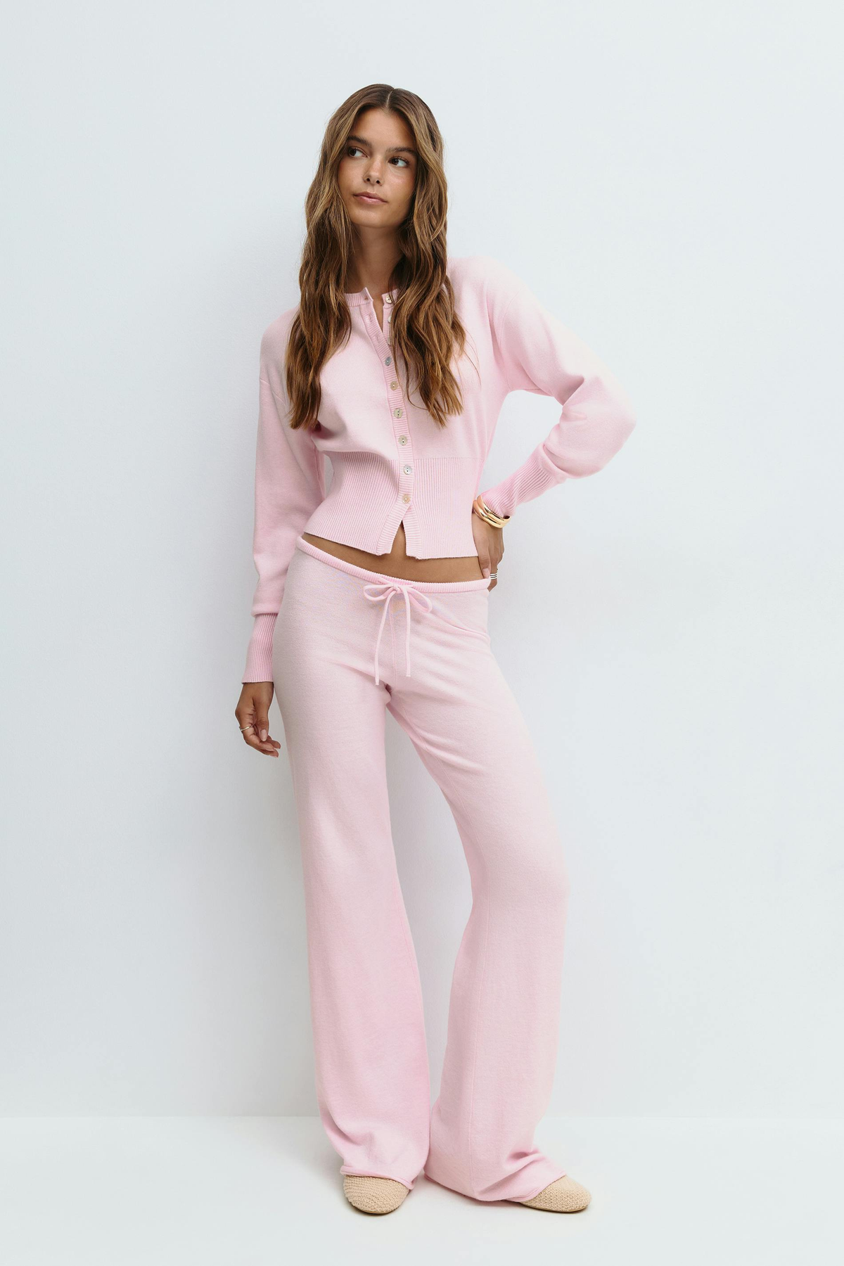 Pink knitted cardigan and trousers set on model, front view