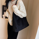 Model carrying the black suede tote bag on her forearm, close-up