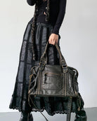 Black vintage-style weave bag held by handles, model in maxi skirt