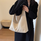 Model carrying the beige suede tote bag on her arm, close-up