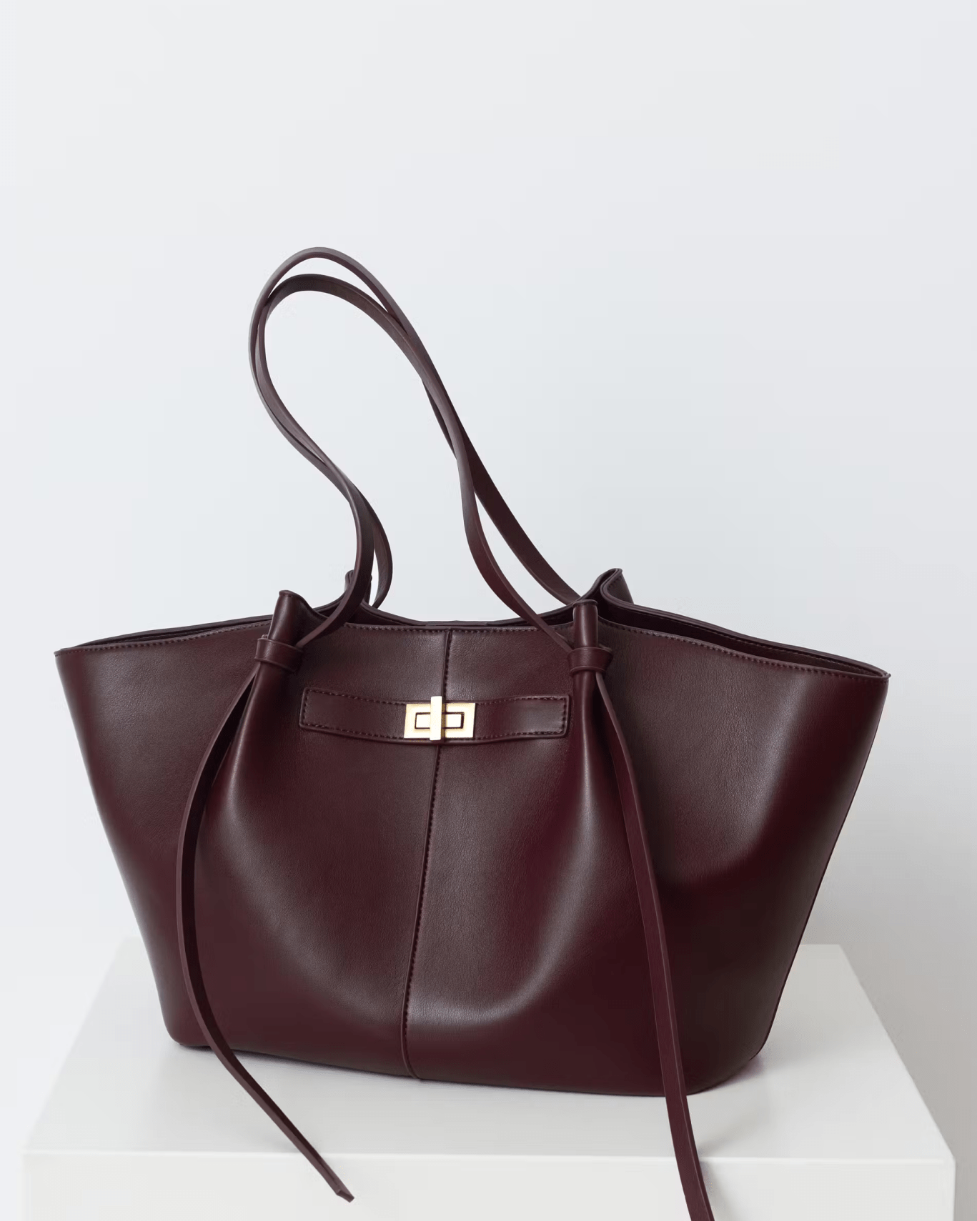 Burgundy leather tote bag with twist-lock strap detail, front view