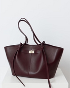 Burgundy leather tote bag with twist-lock strap detail, front view