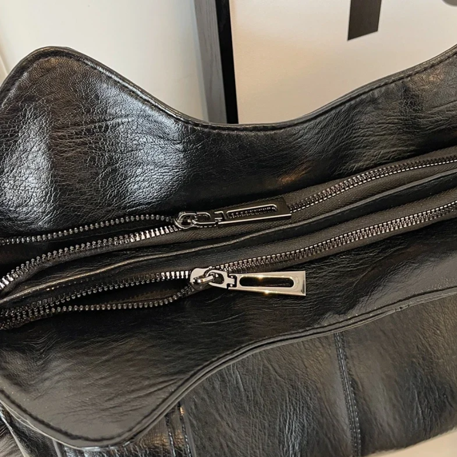 Midnight black leather shoulder bag, close-up of double zip pulls
