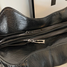 Midnight black leather shoulder bag, close-up of double zip pulls