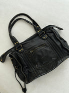 Black vintage-style weave bag laid flat on fabric, angled view
