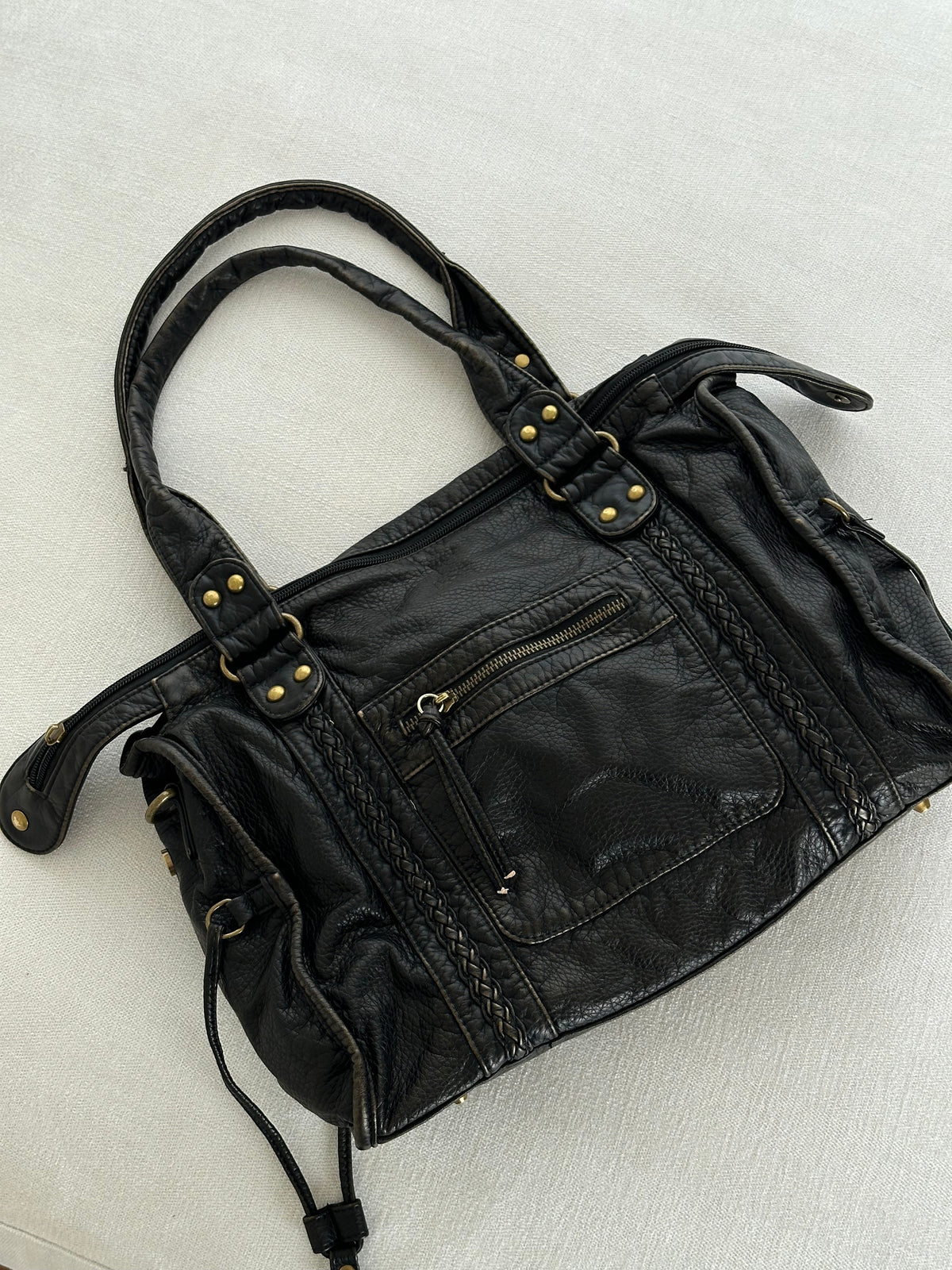 Black vintage-style weave bag laid flat on fabric, angled view