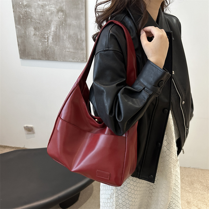 Deep wine leather slouchy shoulder bag worn on model, side view