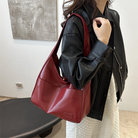 Deep wine leather slouchy shoulder bag worn on model, side view