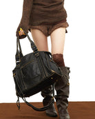 Black vintage-style weave bag held in hand, model wearing boots