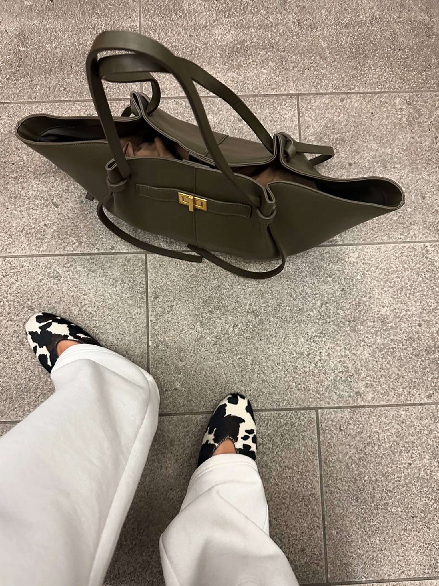 Olive green leather tote bag on floor, top-down view styled shot