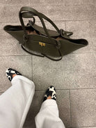 Olive green leather tote bag on floor, top-down view styled shot