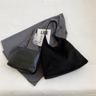 Flat lay of the black suede tote bag with jacket and pouch