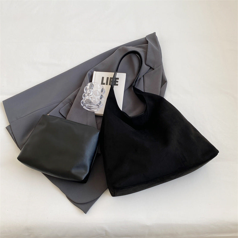 Flat lay of the black suede tote bag with jacket and pouch