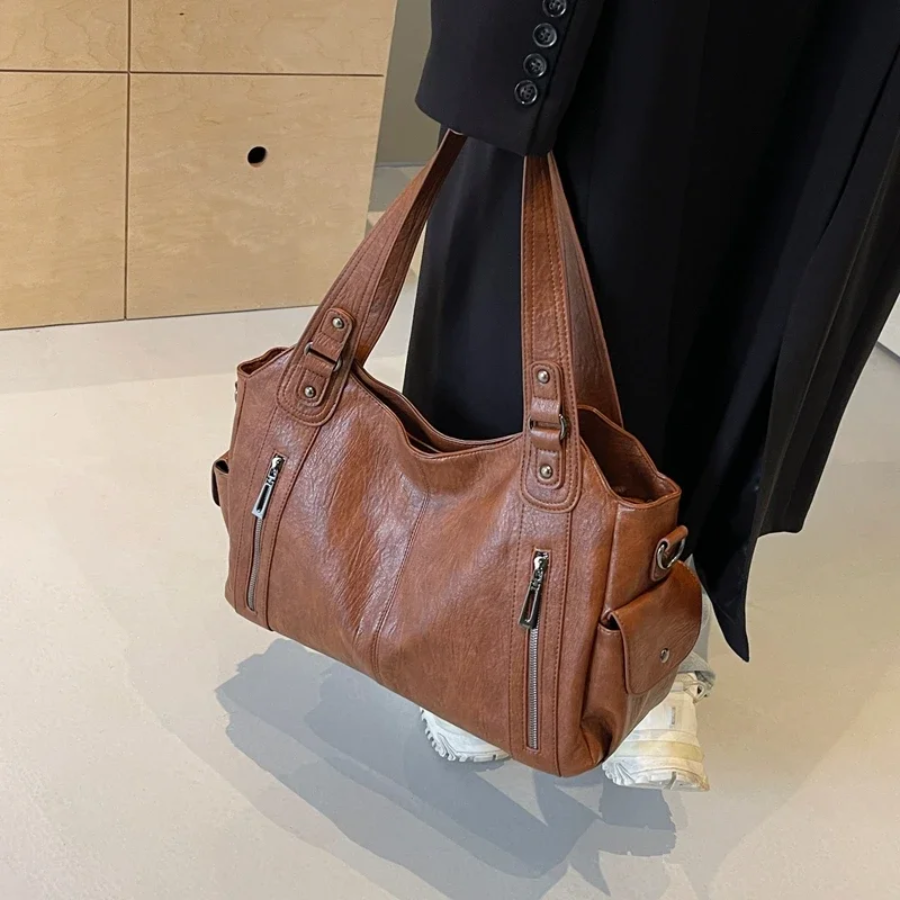 Cognac tan leather shoulder bag held at model's side