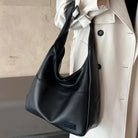 Noir black leather slouchy shoulder bag worn on model, close-up