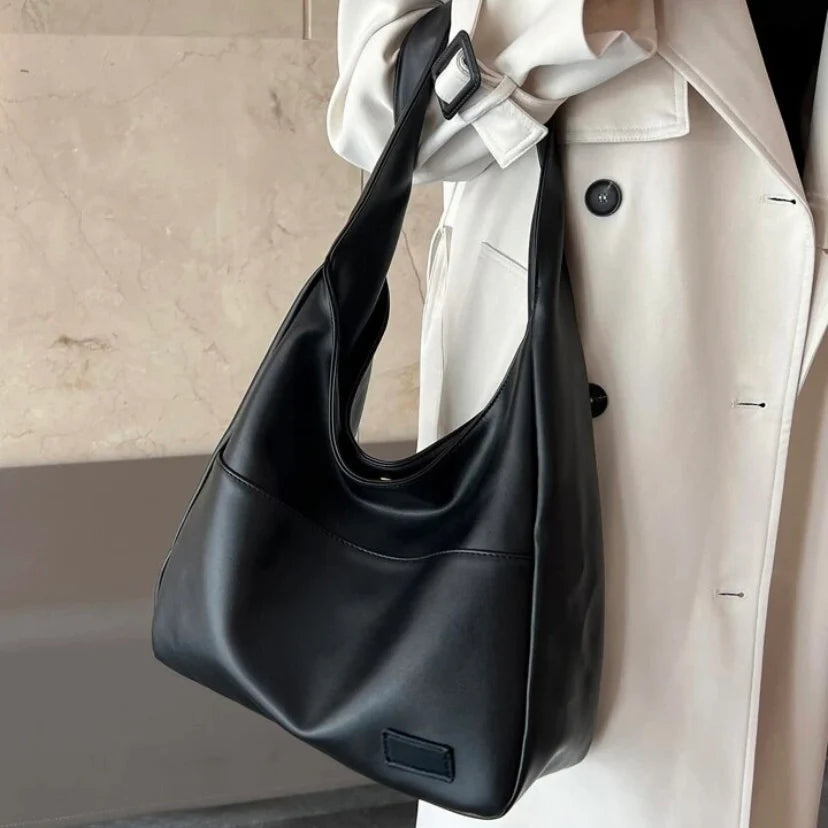 Noir black leather slouchy shoulder bag worn on model, close-up