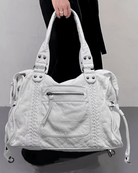 White vintage-style weave bag held by handles, model wearing black