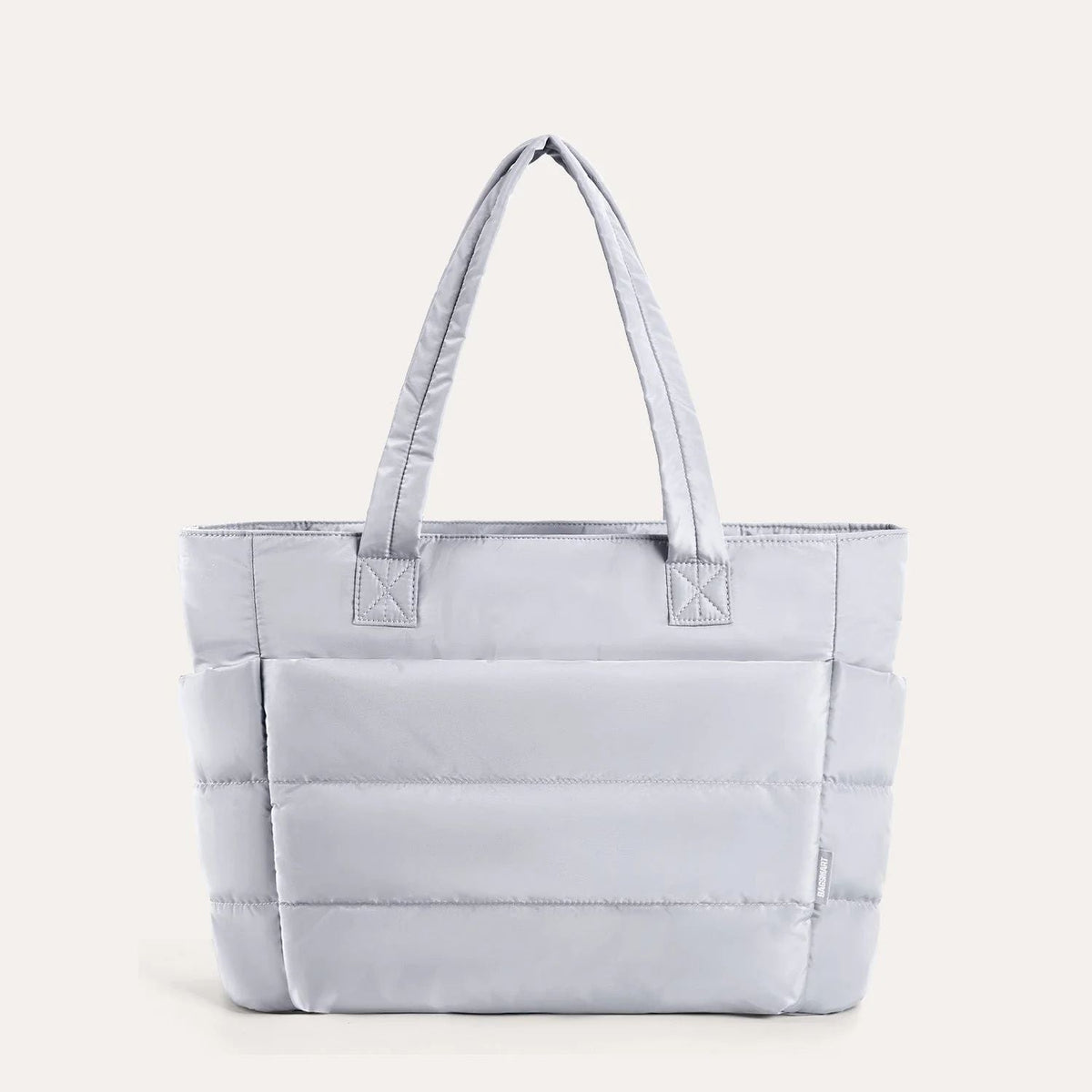 Light grey quilted puffer tote bag, front view on plain background