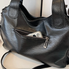 Midnight black leather shoulder bag, close-up of the front zip pocket