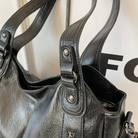 Midnight black leather shoulder bag, close-up of the handles