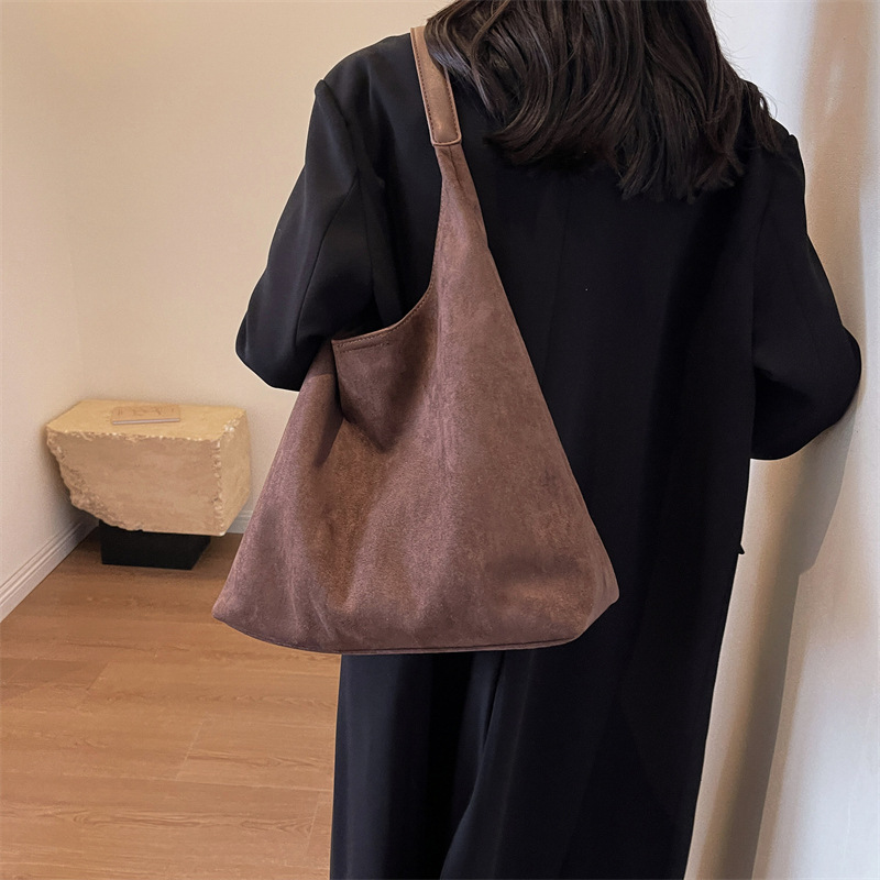 Model wearing the maroon suede tote bag on her shoulder, back view