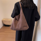 Model wearing the maroon suede tote bag on her shoulder, back view