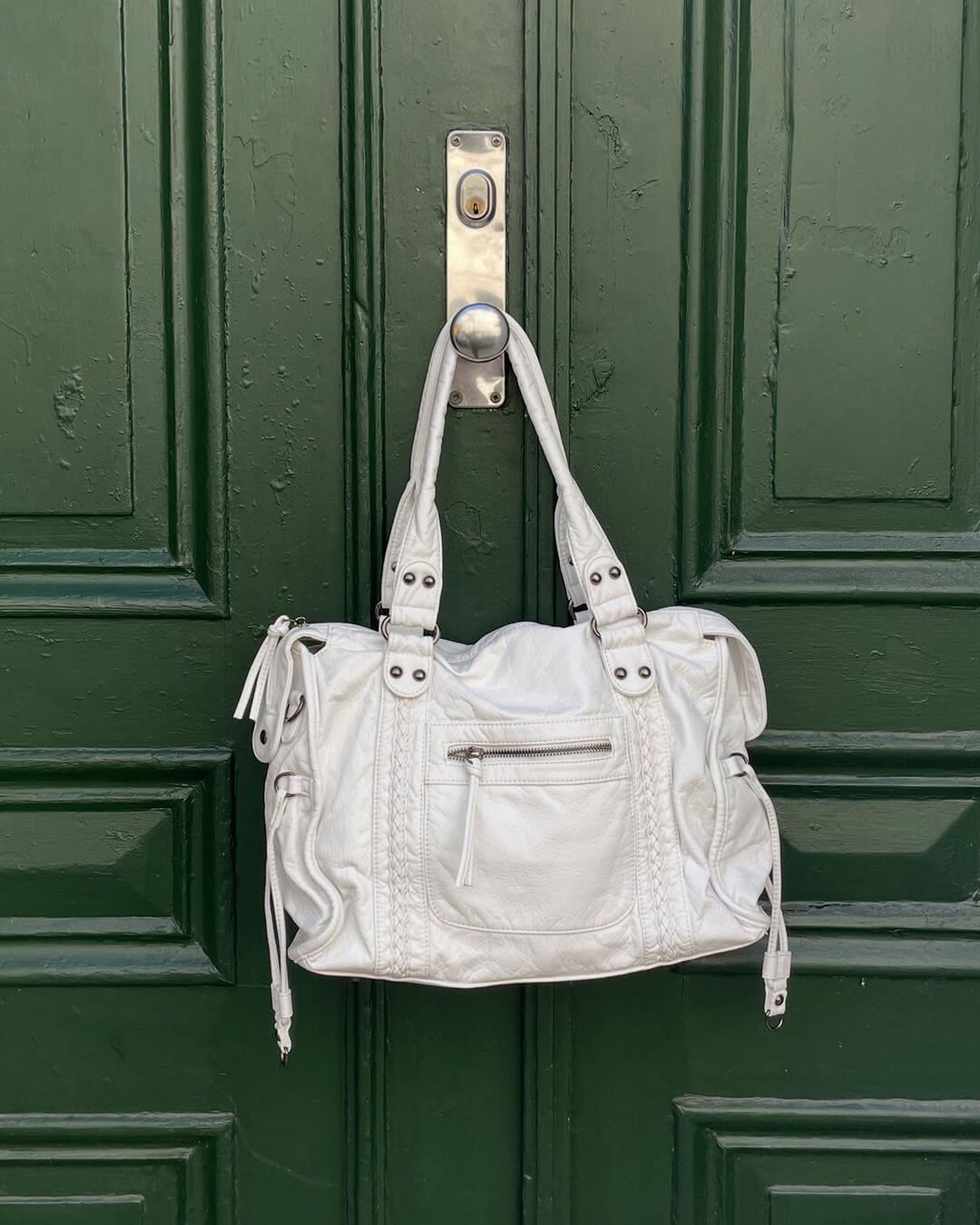 White vintage-style weave bag hanging on green door handle