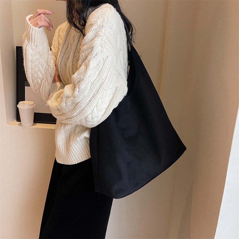 Model wearing the black suede tote bag on her shoulder, side view