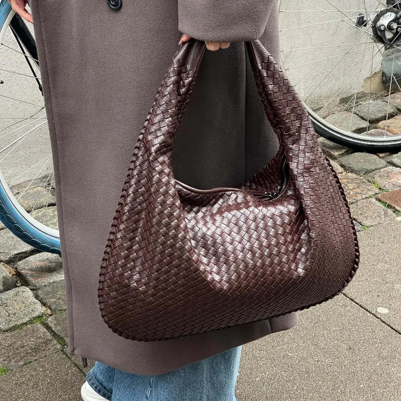 Chocolate brown woven leather hobo bag held by model outdoors