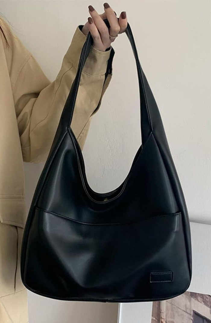 Noir black leather slouchy shoulder bag held on model's arm
