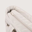 Close-up of the zip pocket on the beige puffer tote bag