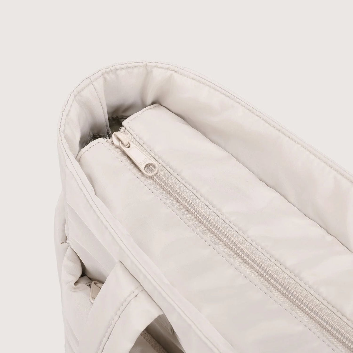 Close-up of the zip pocket on the beige puffer tote bag