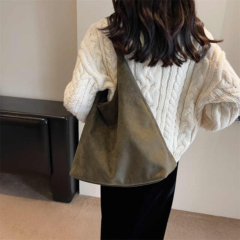Model wearing the green suede tote bag over her shoulder, back view